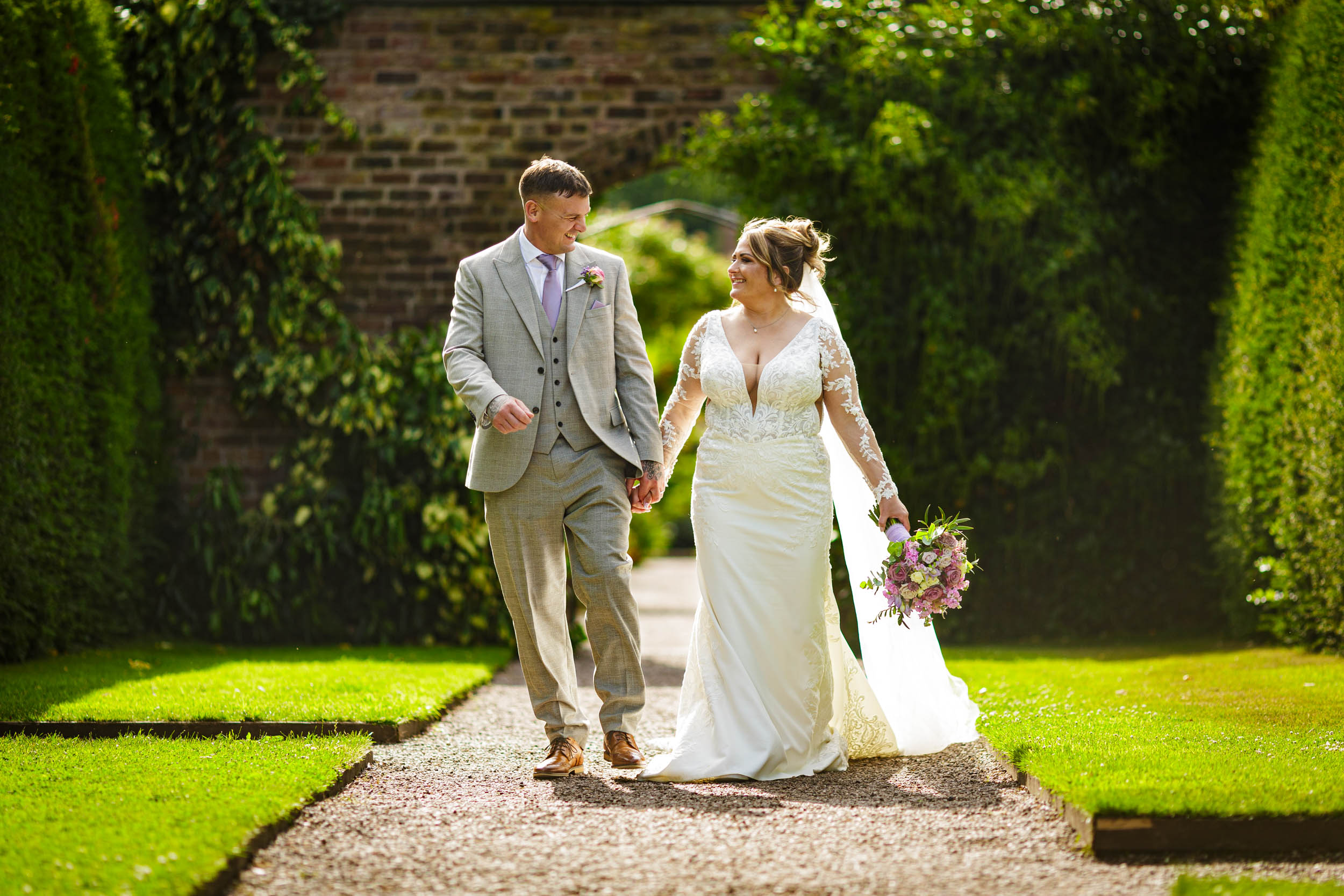 Bride and groom walking through gardens at Arley Hall