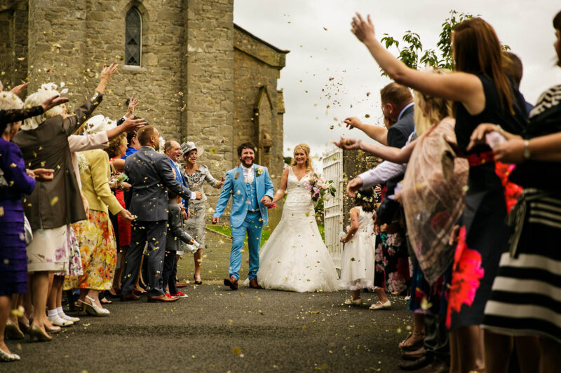 Bride and groom kissing walking through confetti