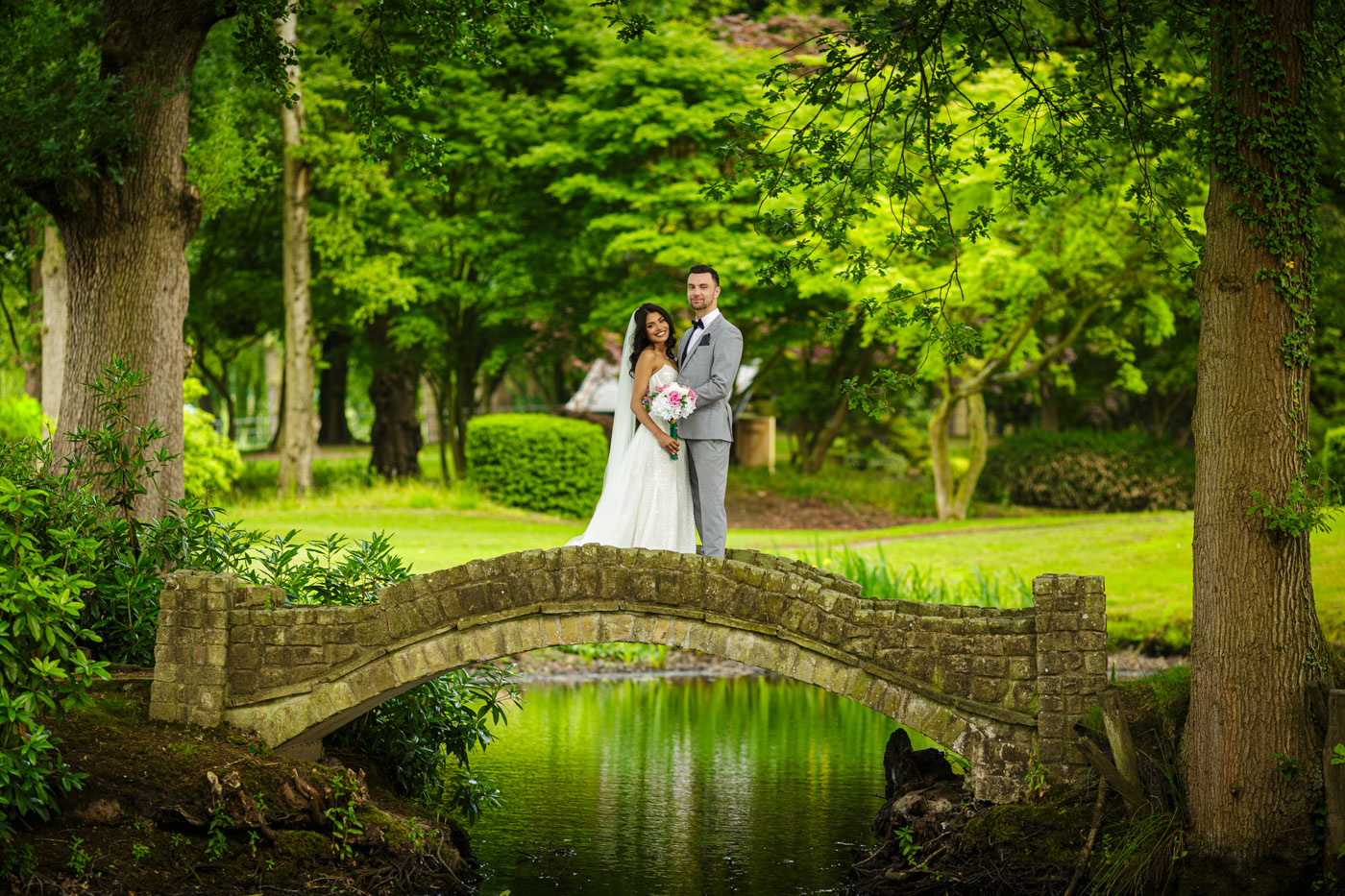 bride and groom on bridge in gardens at colshaw hall