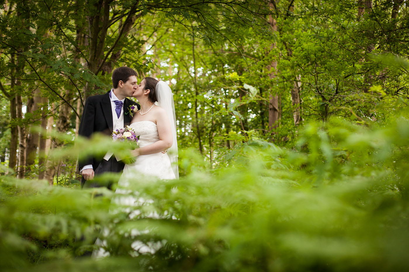bride and groom kissing in woods at nunsmere hall