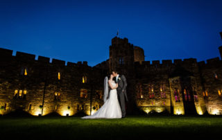 bride and groom kissing in front of peckforton castle