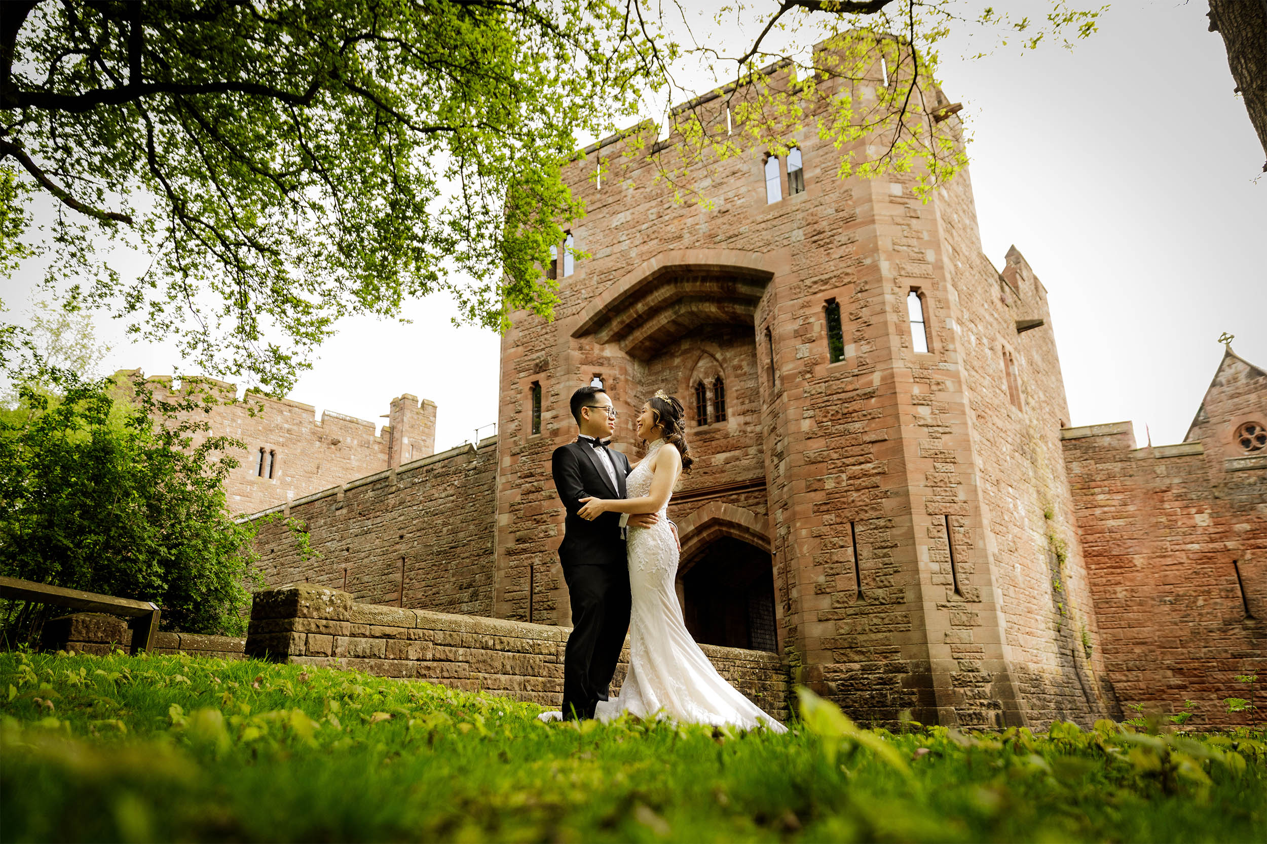 Bride and groom posing in front of Peckforton Castle entrance