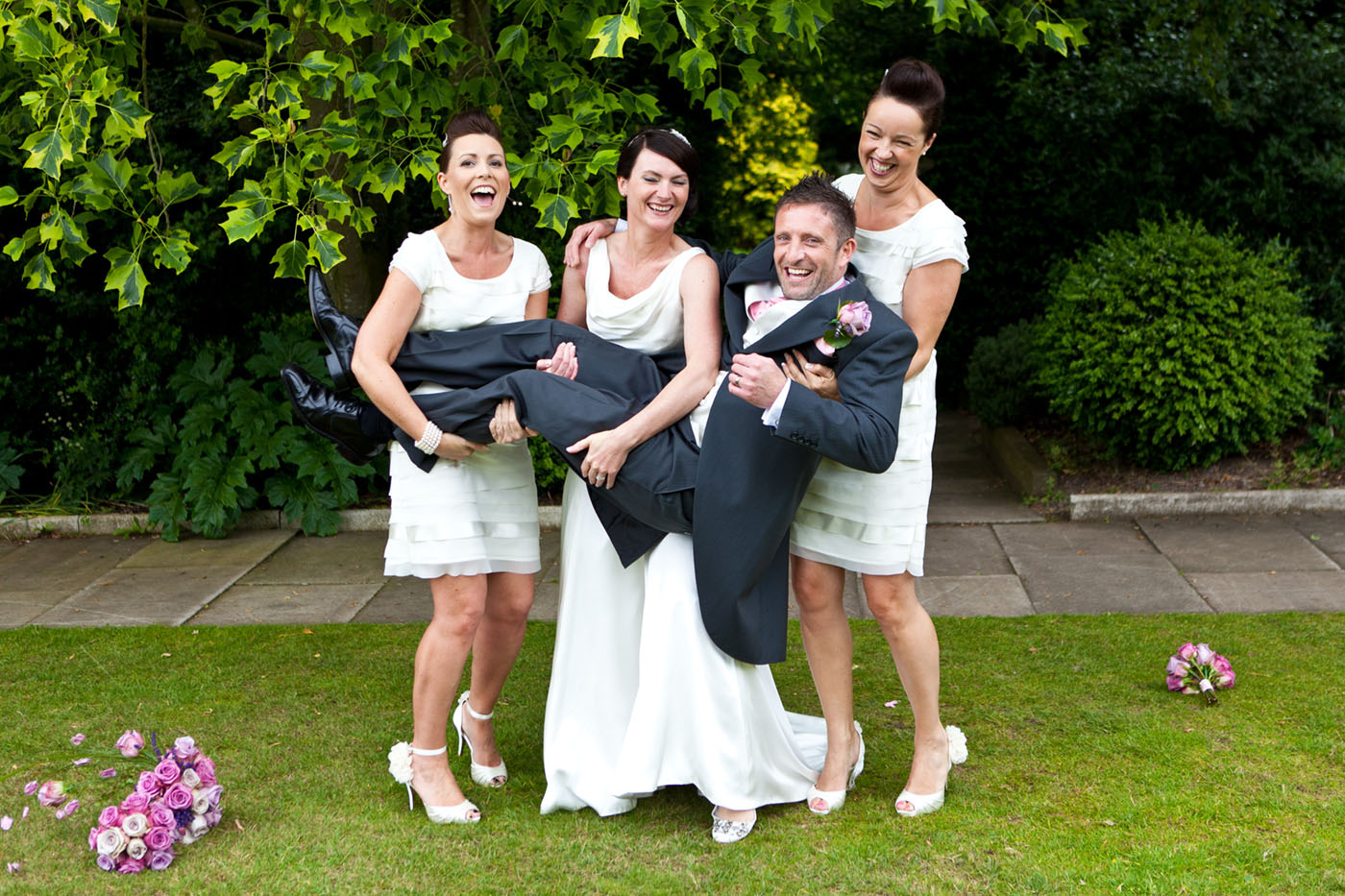 bride and bridesmaid holding groom up at rowton hall wedding