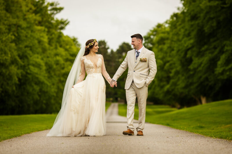 bride and groom holding hands on drive at soughton hall