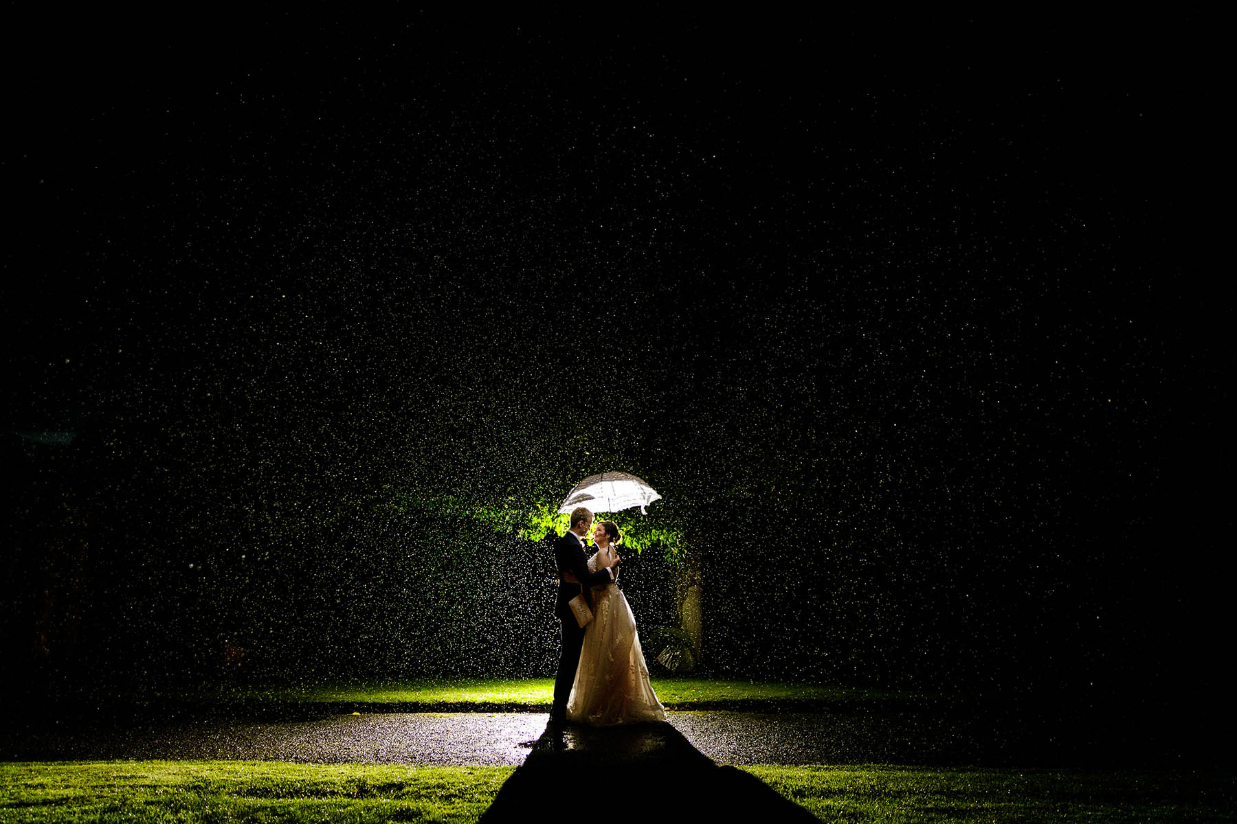 bride and groom under umbrella in rain